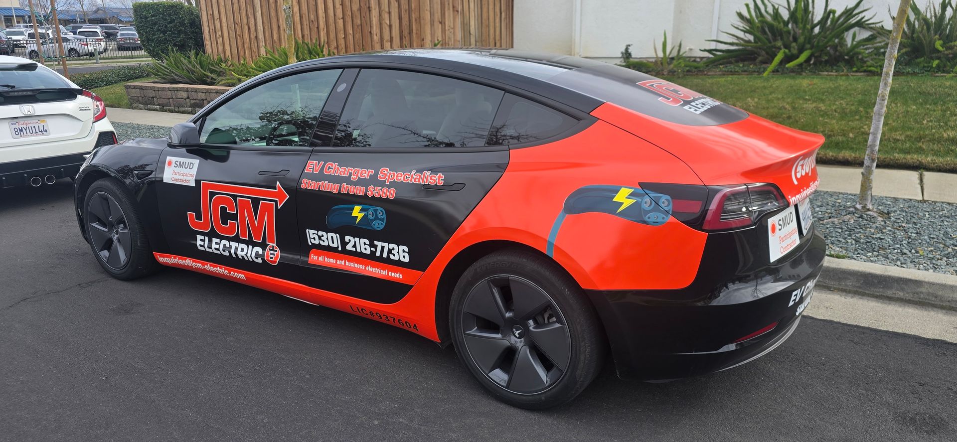 Black sedan with red racing decals parked on a roadside