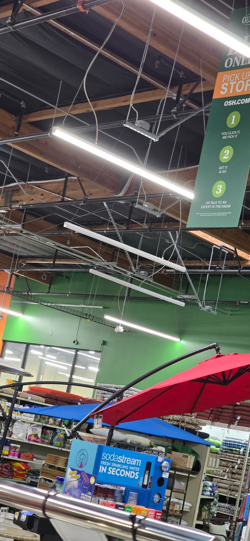 Indoor market with exposed ceiling lights, hanging signs, green walls, and a red umbrella in the foreground