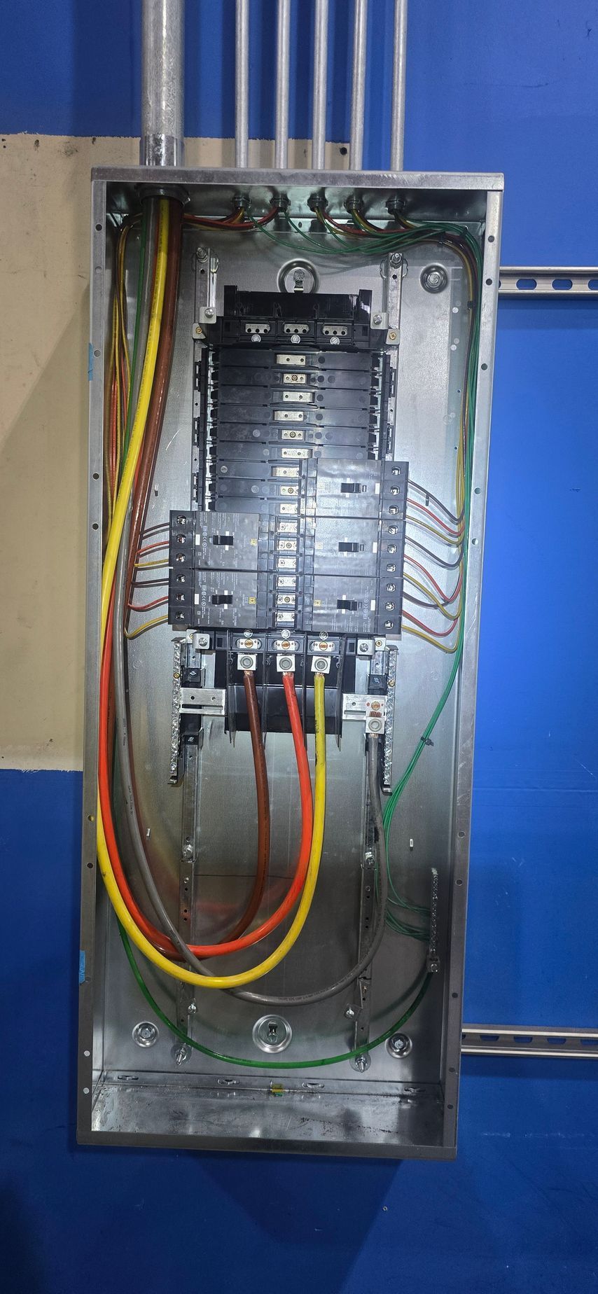 Open electrical breaker panel with exposed wiring in a metal cabinet