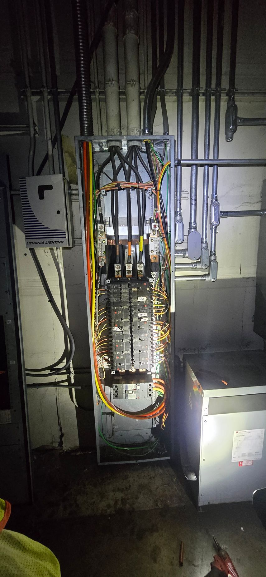 Electrical control panel with exposed wiring and circuit breakers in a utility room.