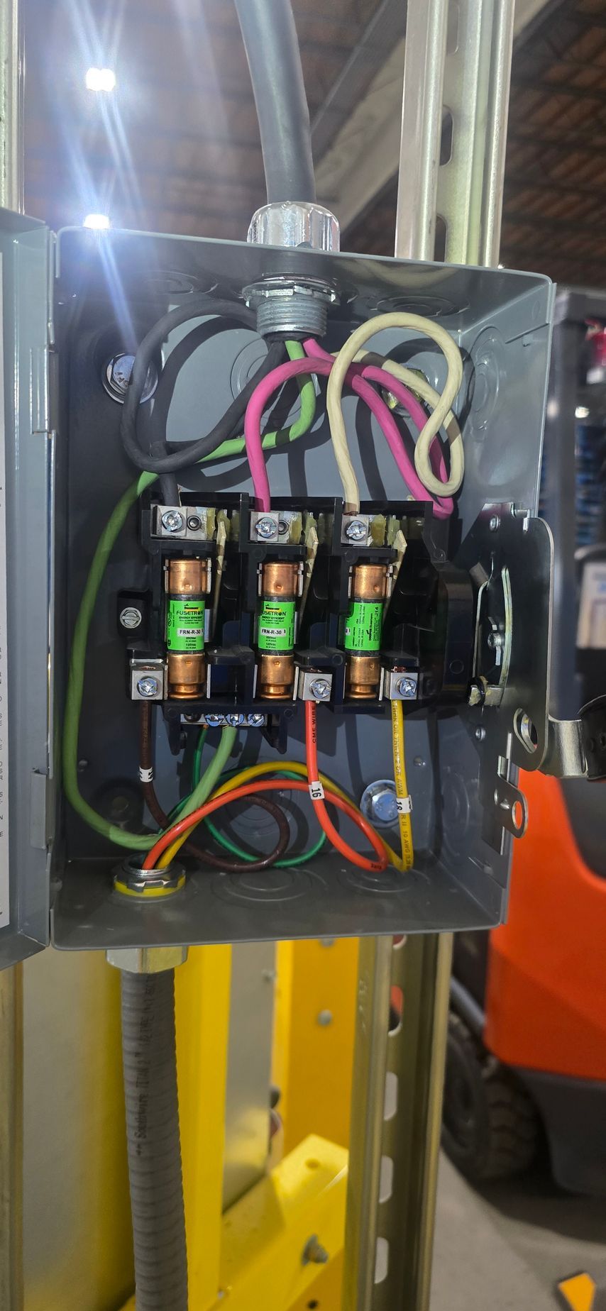 Open electrical control box with colored wires, relays, and switches mounted inside a metal cabinet.