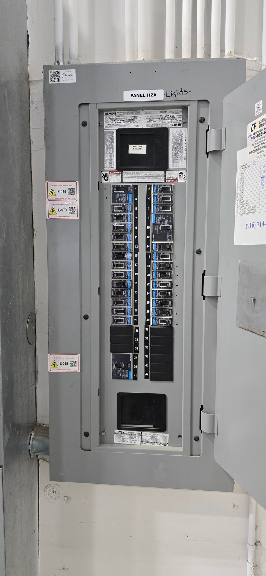 Open electrical breaker panel with rows of circuit breakers and exposed wiring