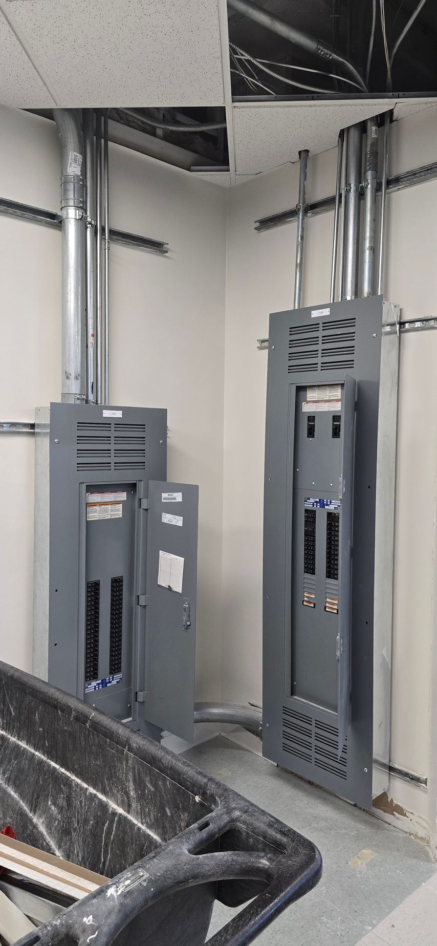 Electrical panels and conduit in a utility room with unfinished walls and a concrete floor