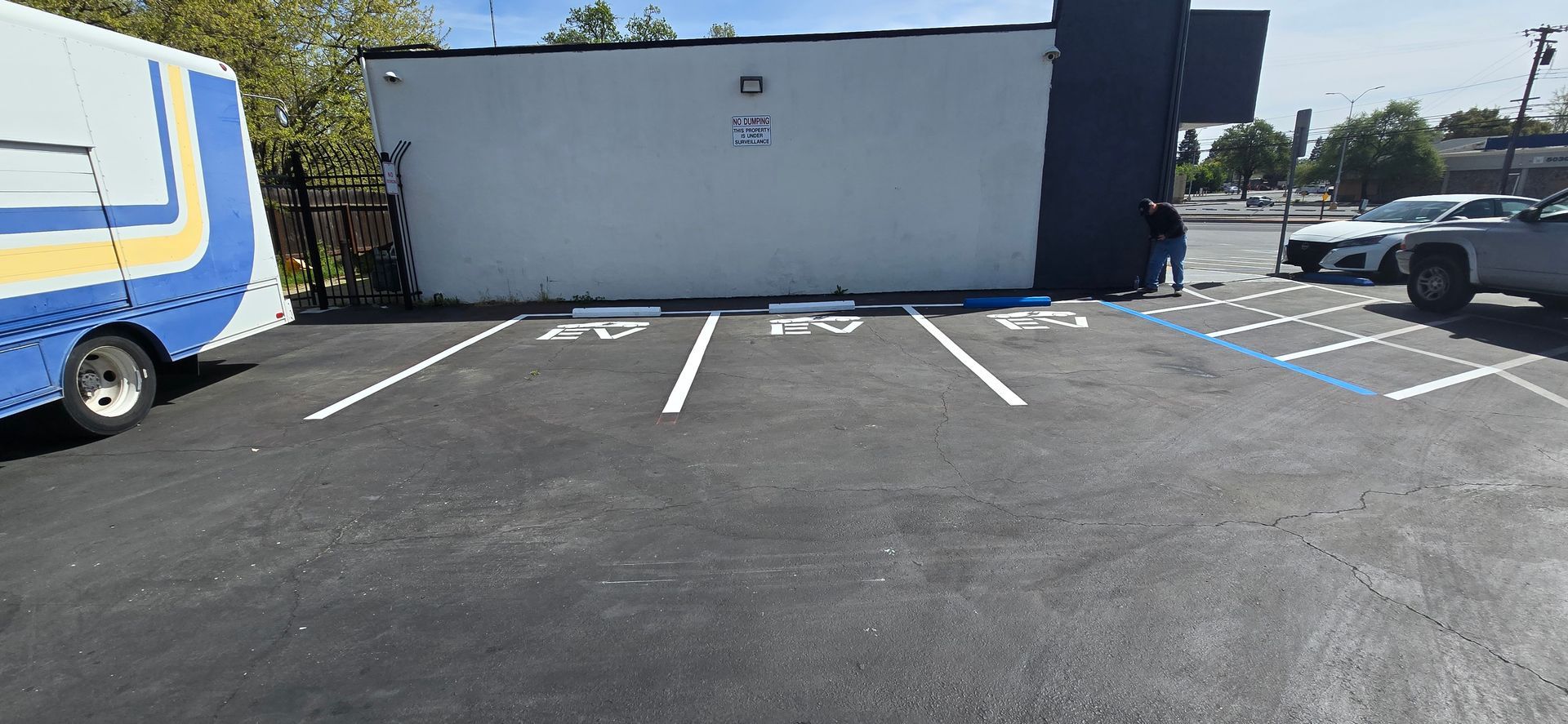 Empty parking lot with painted white spaces beside a white building on a sunny day