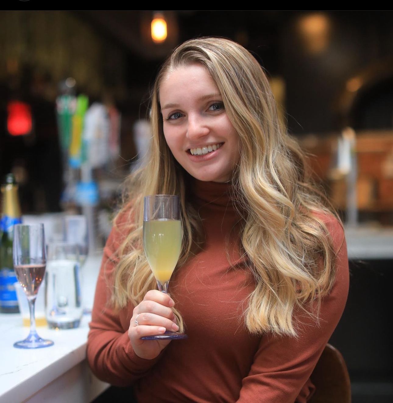 A woman is holding a glass of wine and smiling