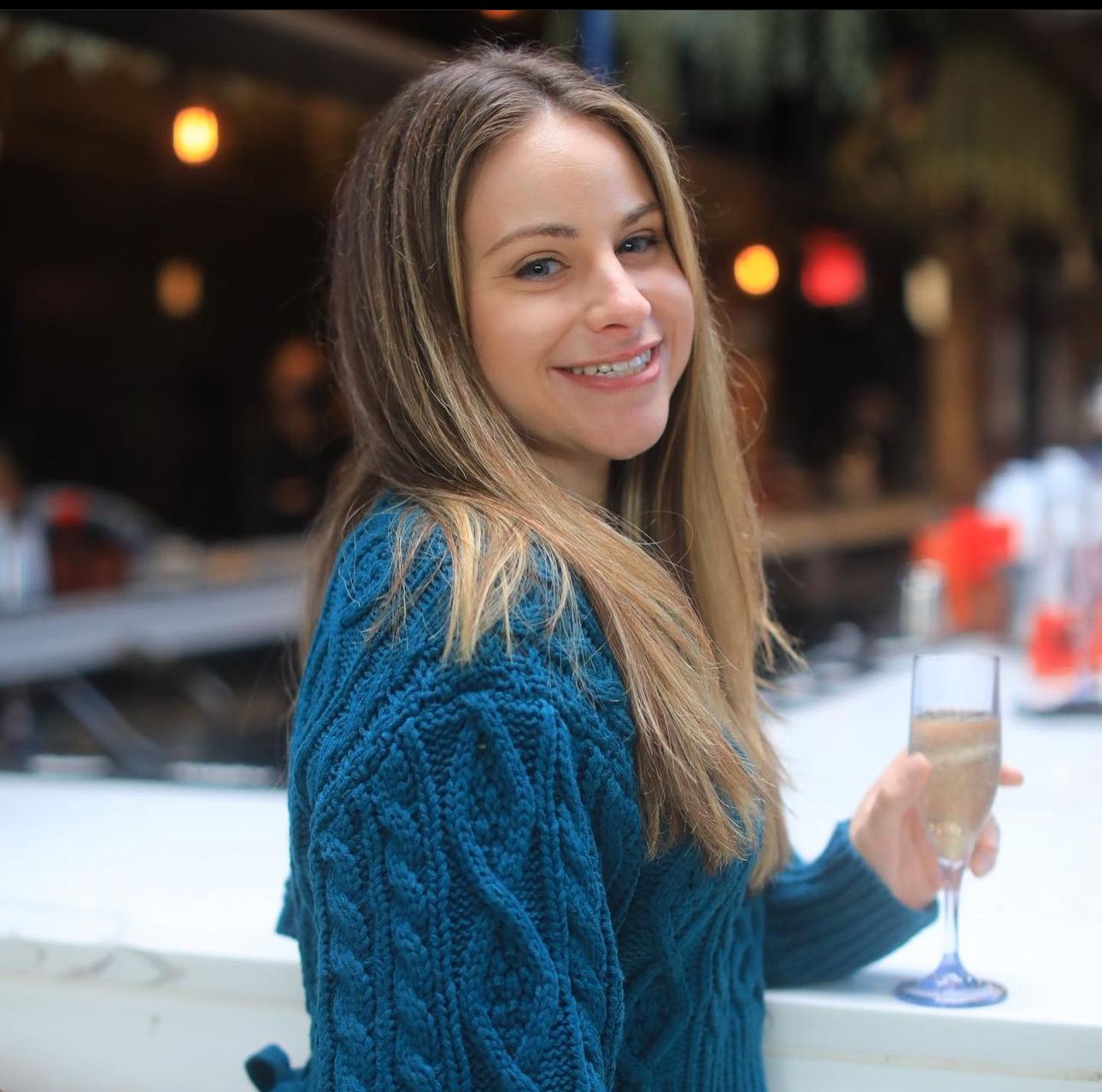 A woman in a blue sweater is holding a glass of champagne