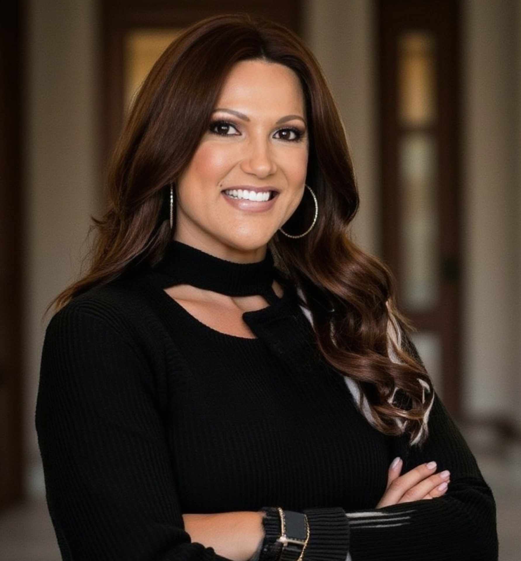 A woman is sitting at a desk with a laptop and a vase of flowers.