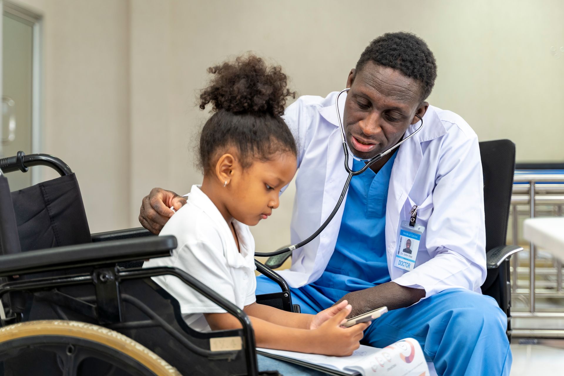 Black male doctor assisting black child in wheelchair