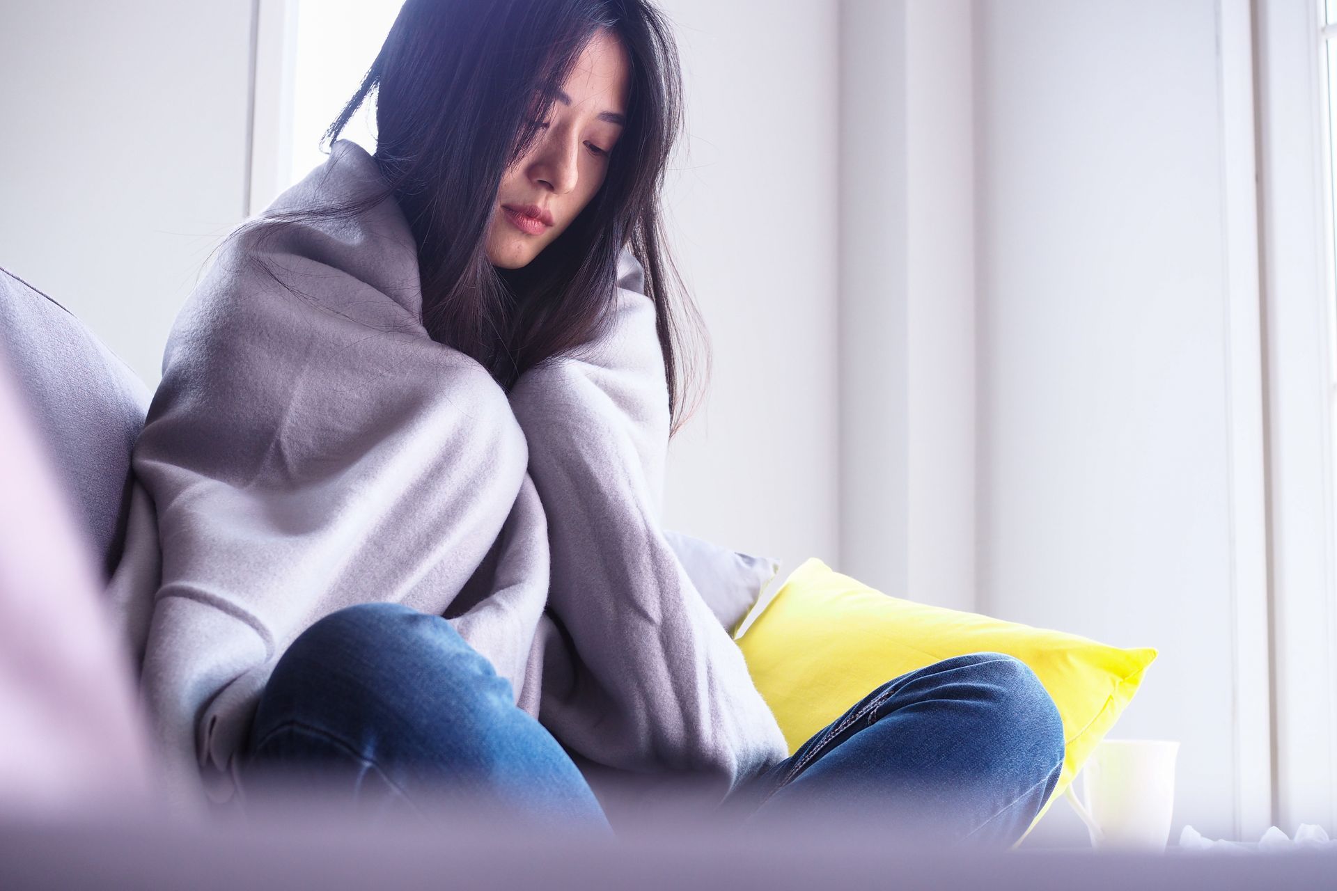 lonely Asian woman wrapped in blanket, looks sad