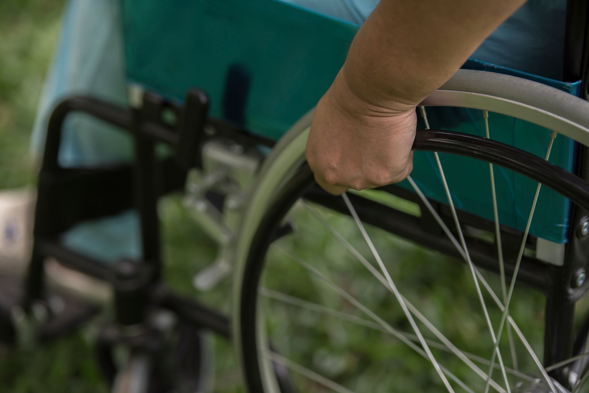 white man or womans hand and arm up close on wheelchair wheel