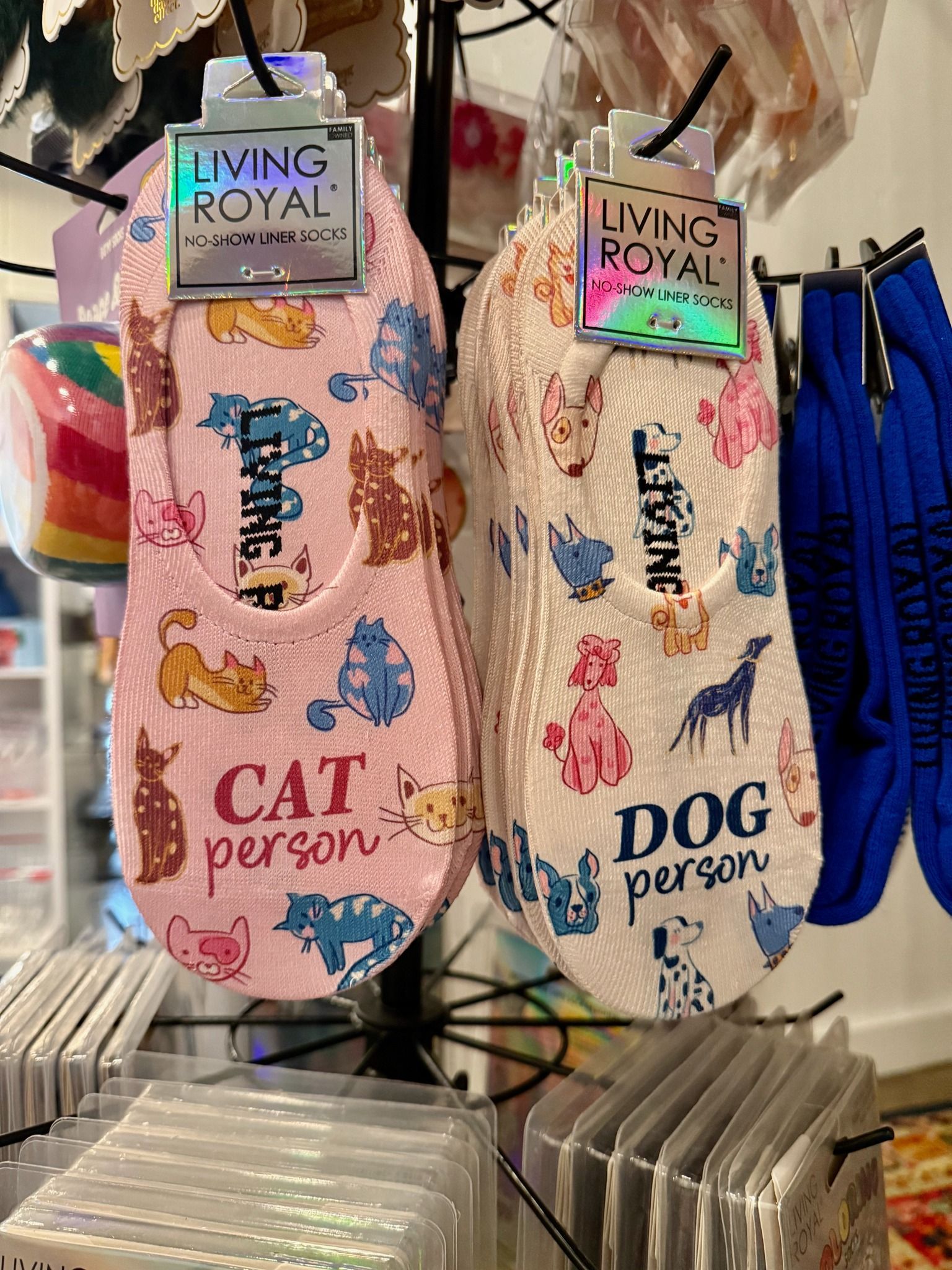 A pair of socks with cats and dogs on them are hanging on a rack.
