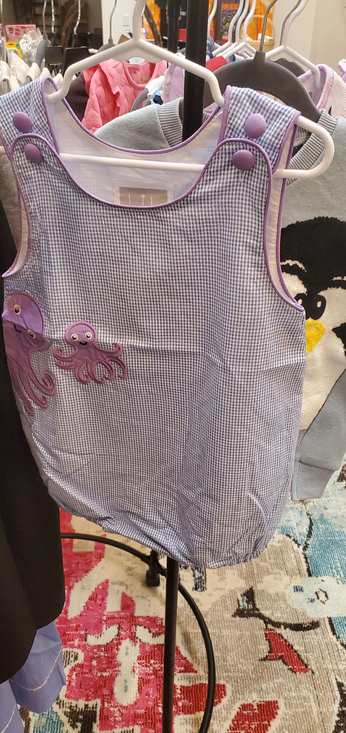 A purple and white dress is hanging on a hanger in a store.