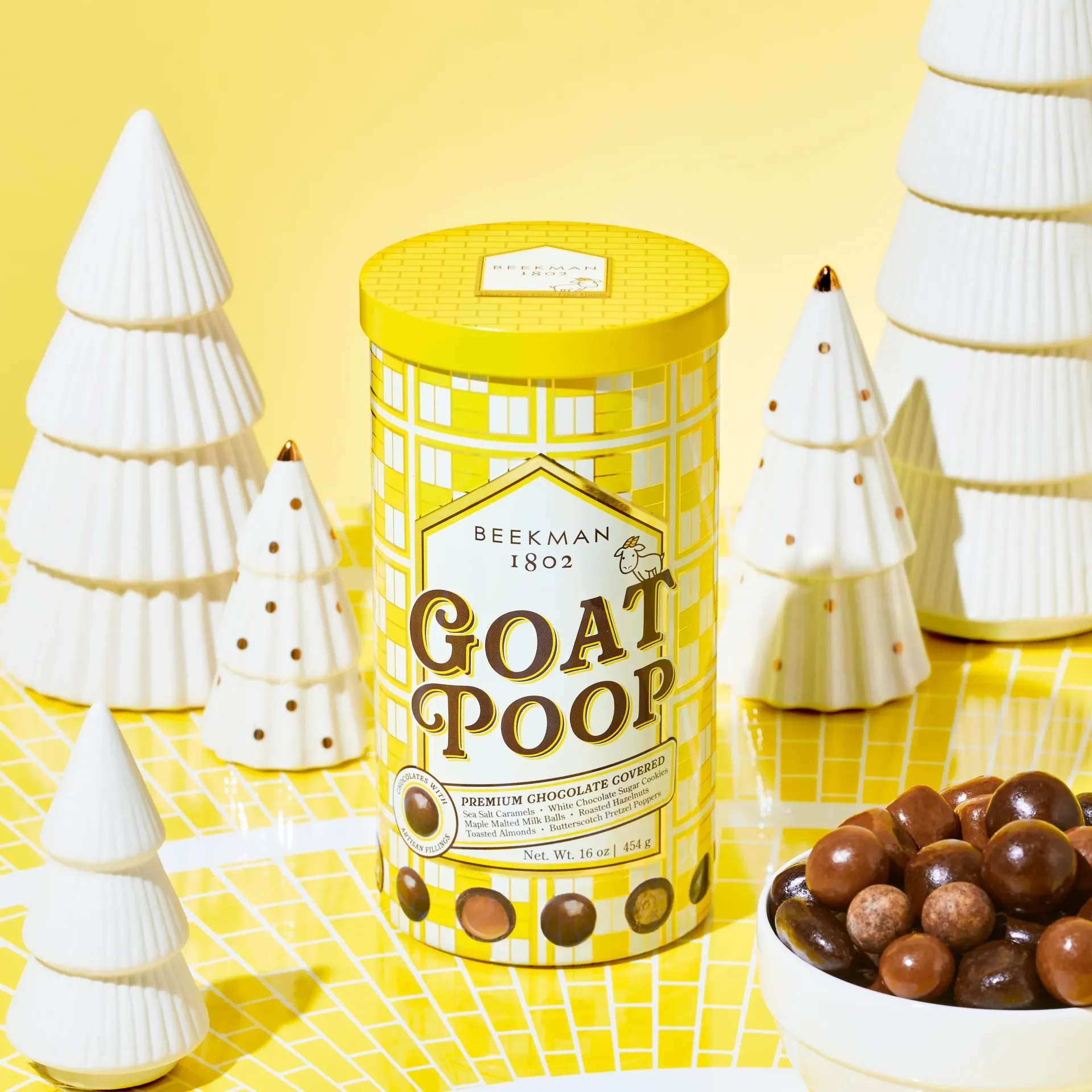 A yellow can of goat poop surrounded by christmas trees