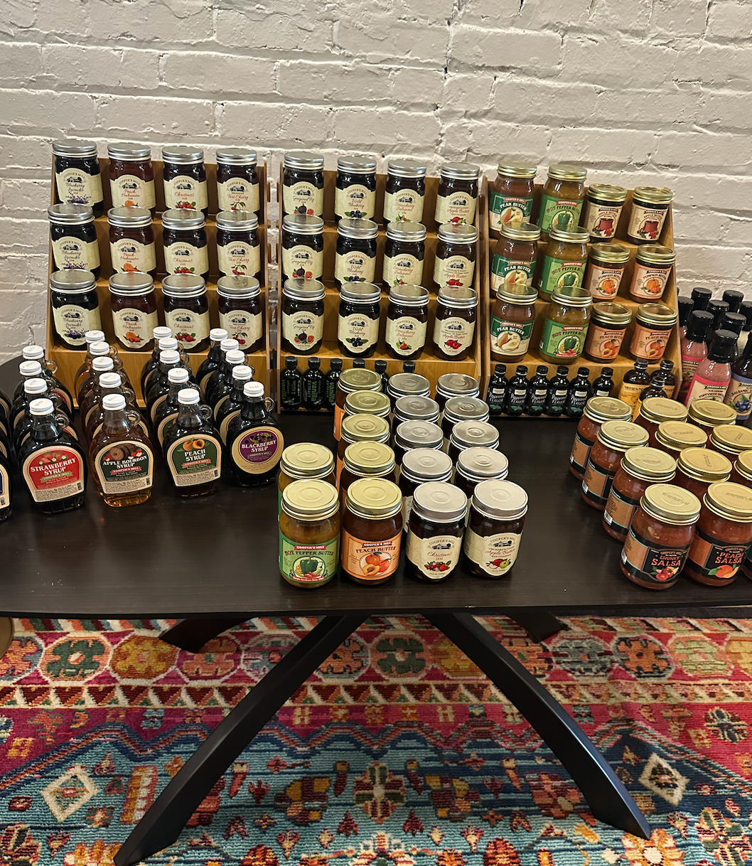 A table filled with jars and bottles of maple syrup, jams, jellies, and more.