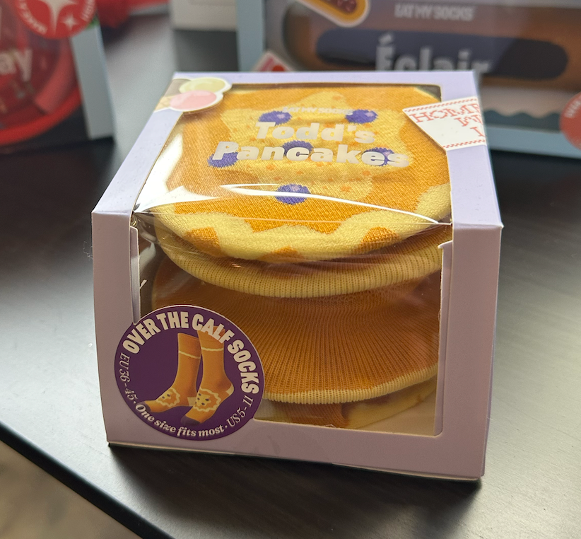 A box of todd 's pancake socks - a style from Eat My Socks sits on a table at Treasure - The Gift Store.