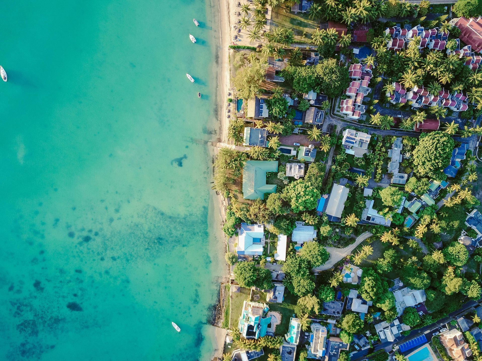 An aerial view of a tropical beach with a lot of buildings and trees.