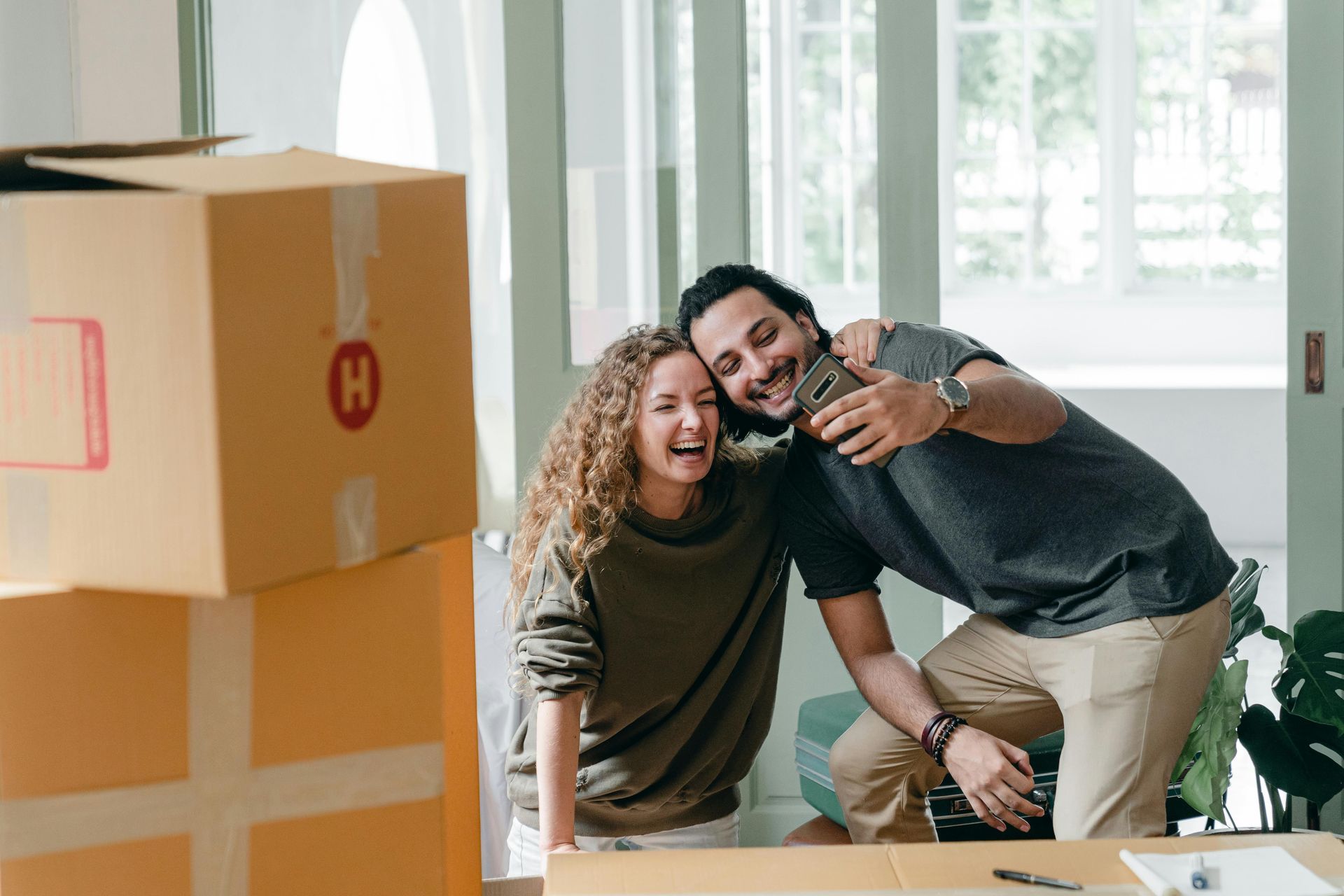 A man and a woman are taking a selfie in their new home.