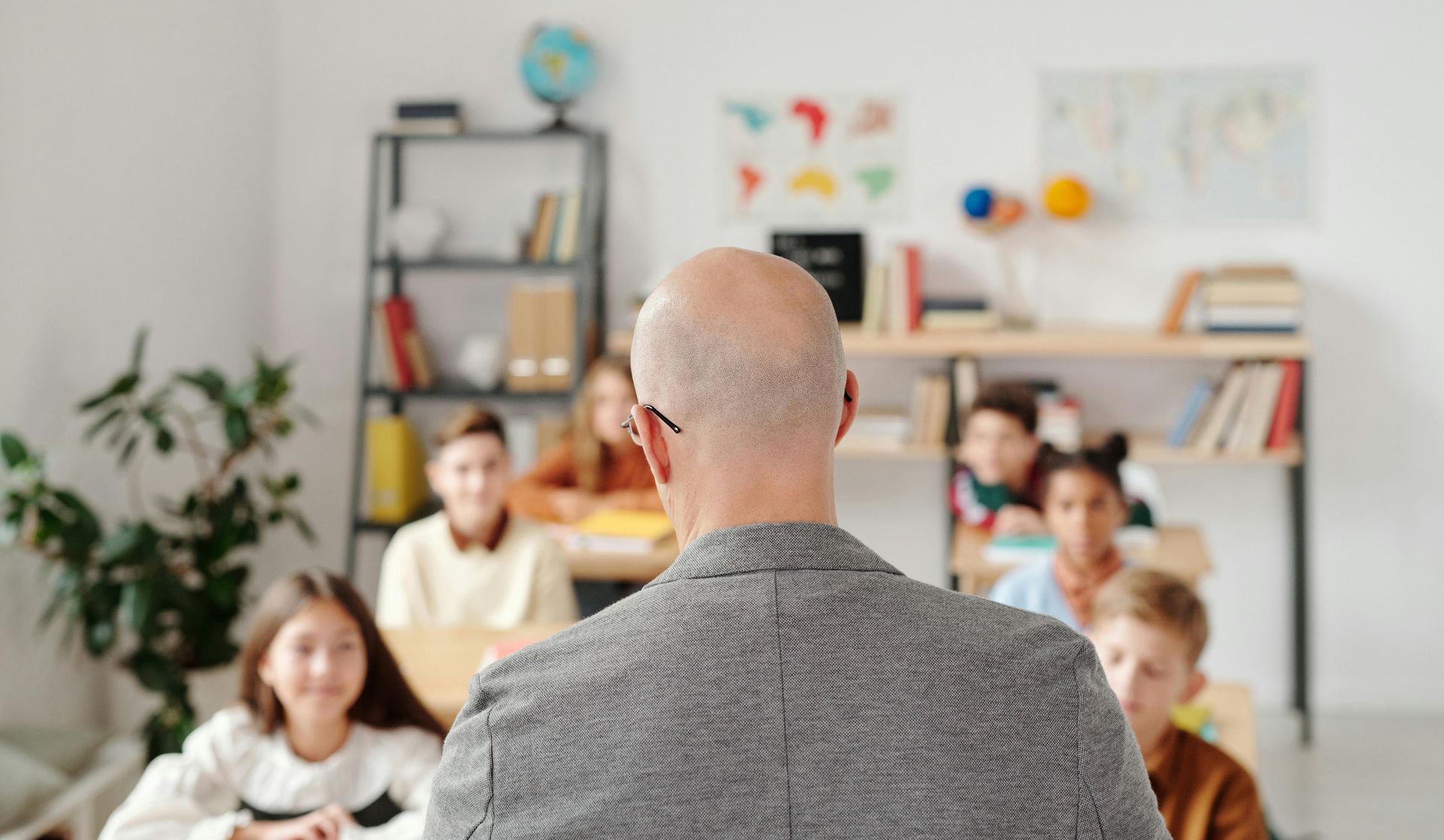 A man is giving a presentation to a group of children in a classroom.