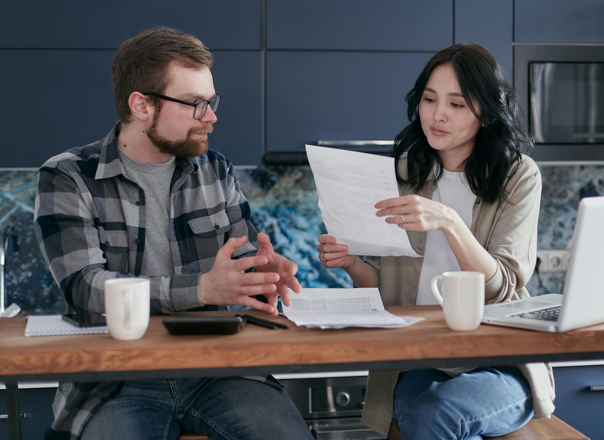 A man and a woman are sitting at a table looking at papers.