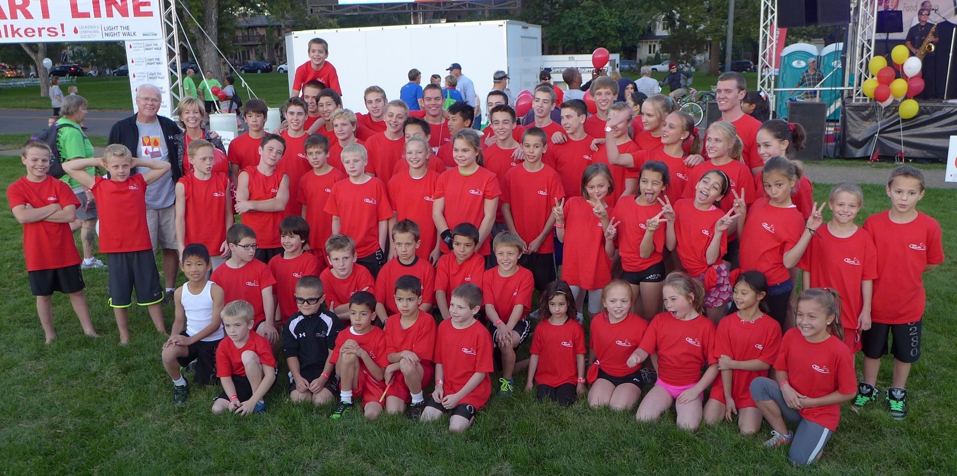 A large group of children in red shirts are posing for a picture