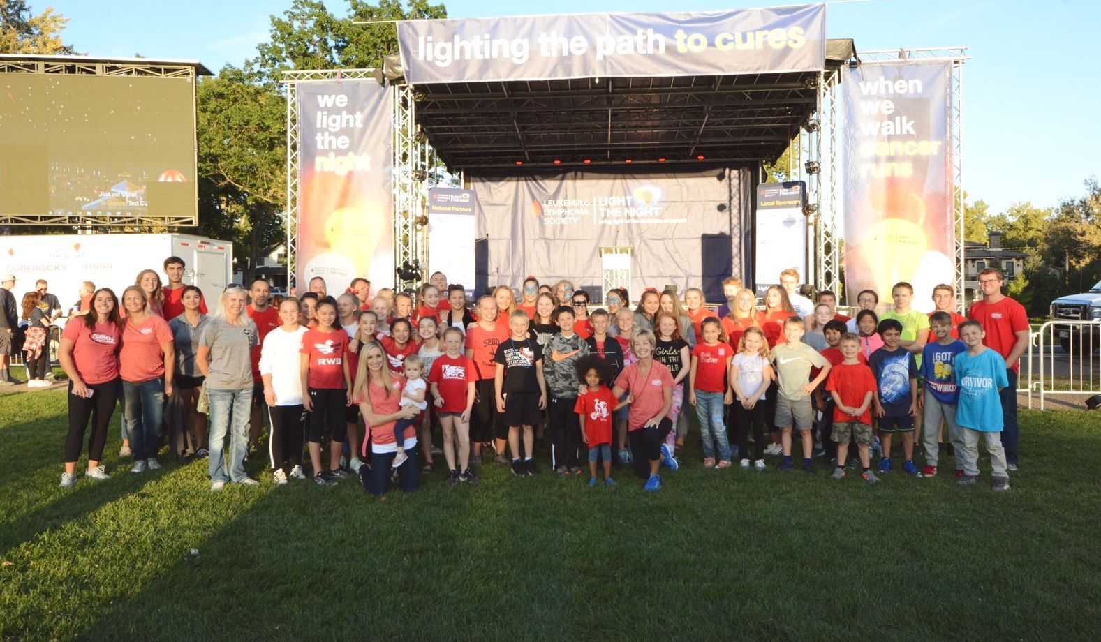 A large group of people standing in front of a stage that says lighting the path to cures