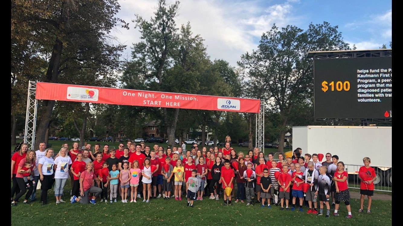 A large group of people standing in front of a sign that says $ 100