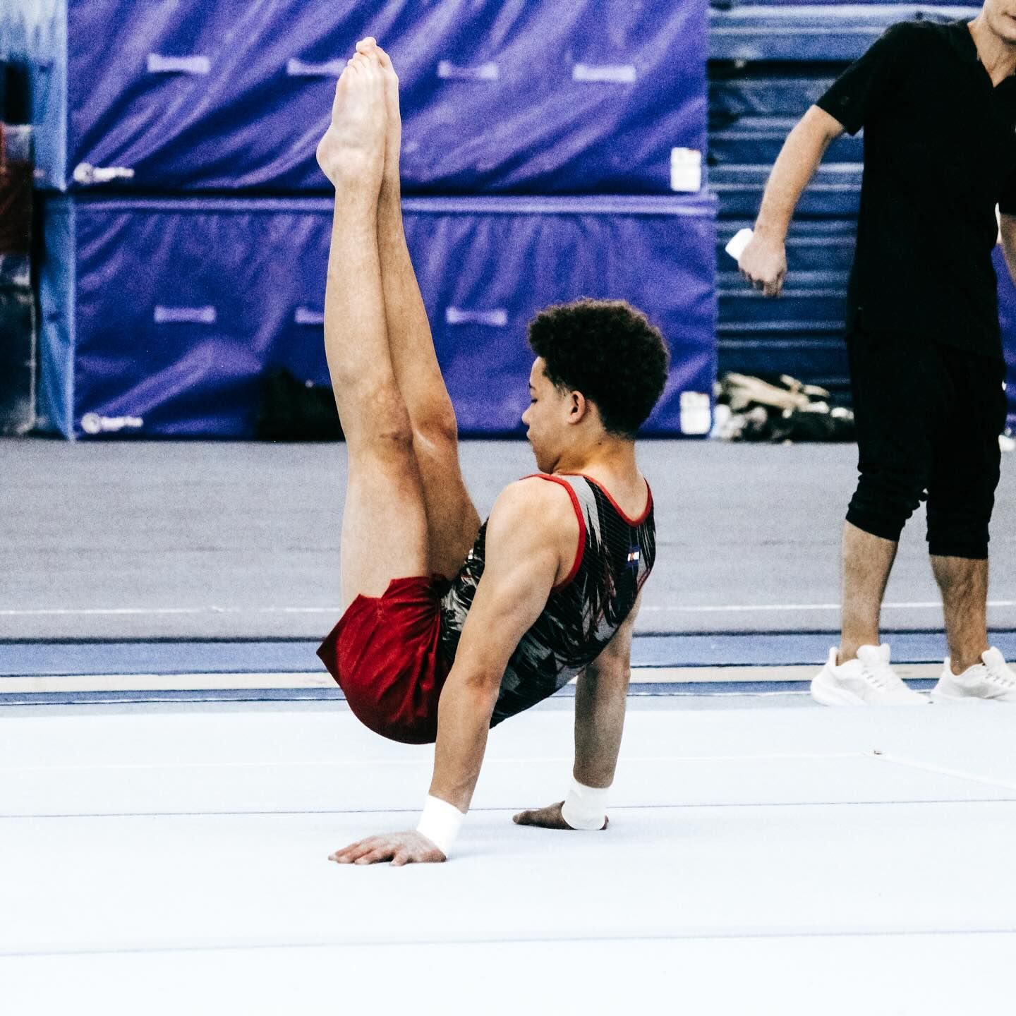 A man is doing a handstand on a gym floor