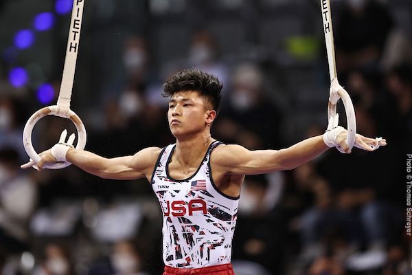 A man is doing a routine on a pair of gymnastic rings.