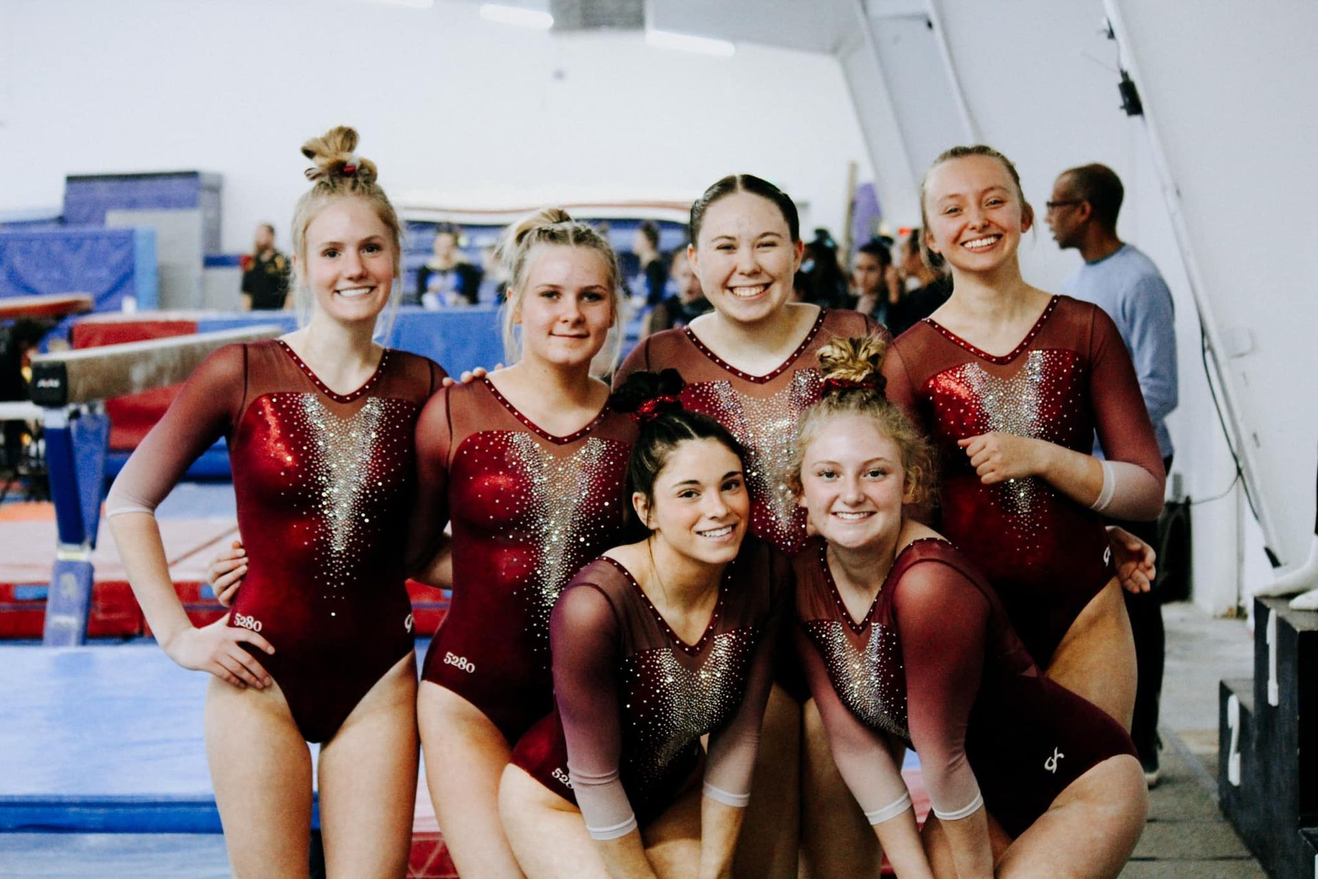 A group of female gymnasts are posing for a picture in a gym.