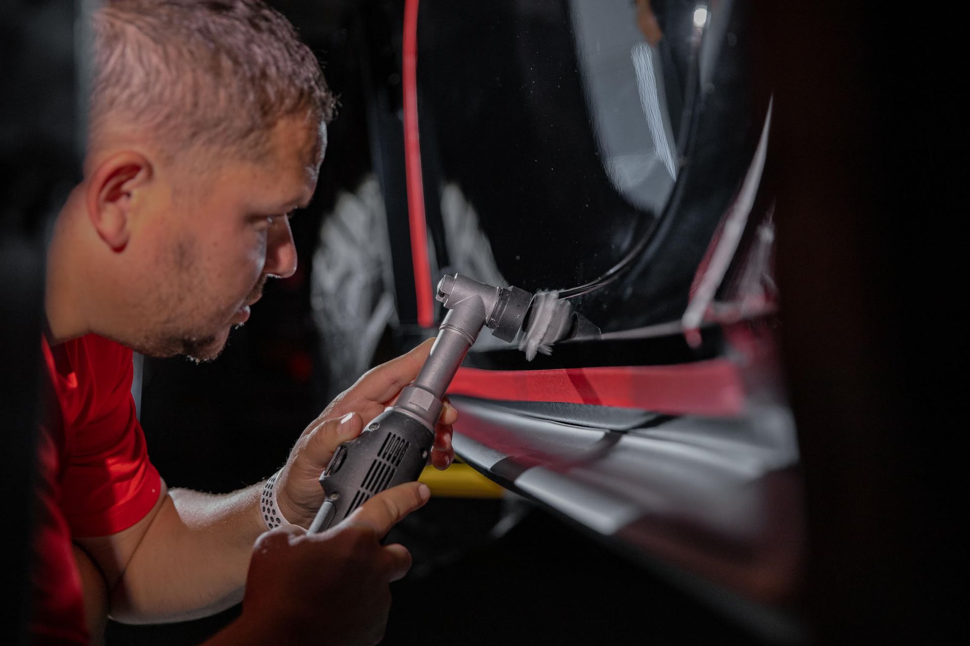 A man is polishing a car with a machine.