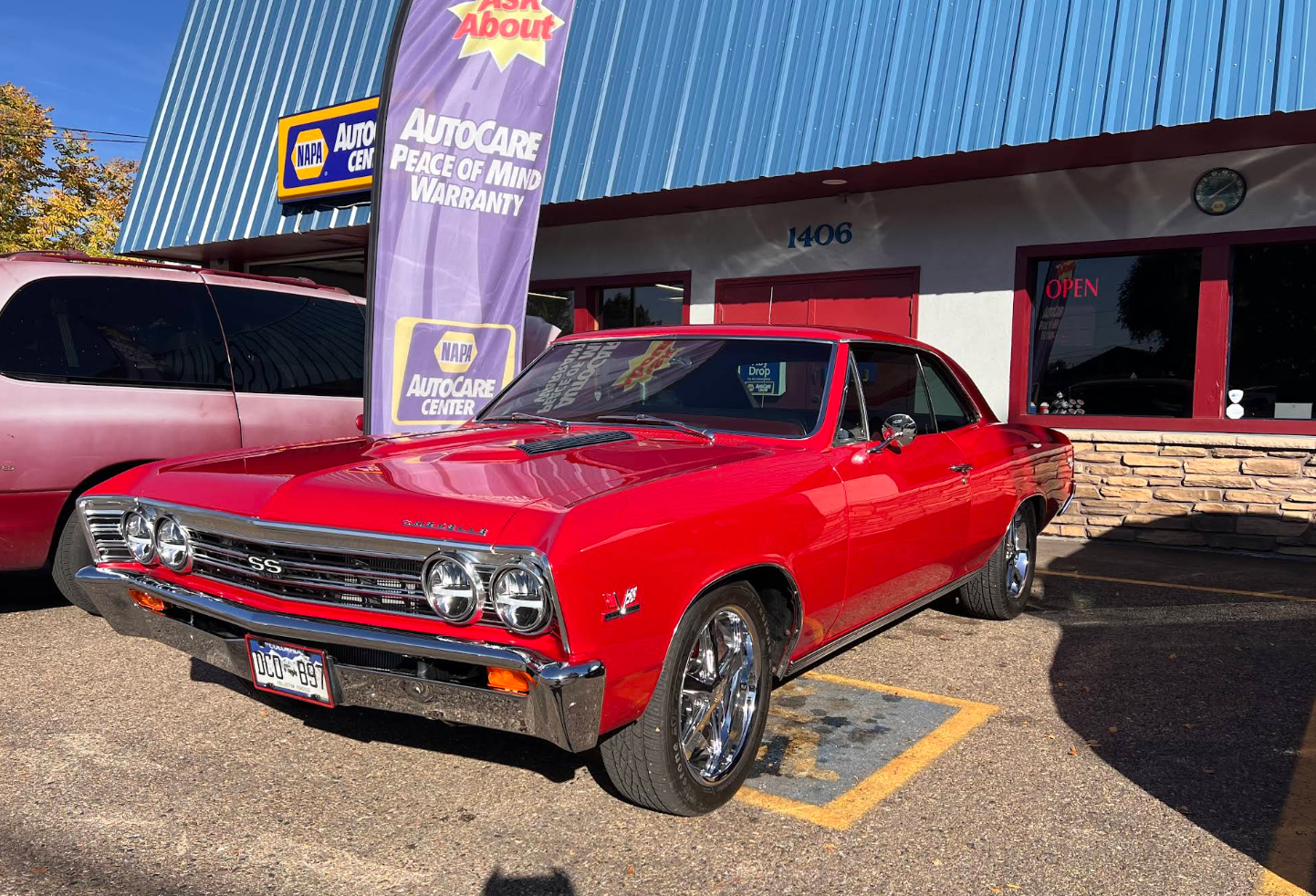 A red car is parked in front of a car dealership. | Carworks