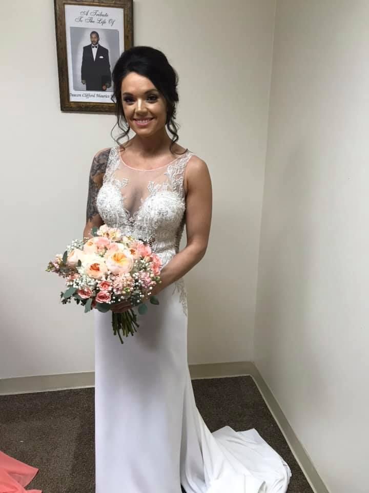 a woman in a wedding dress is holding a bouquet of flowers .