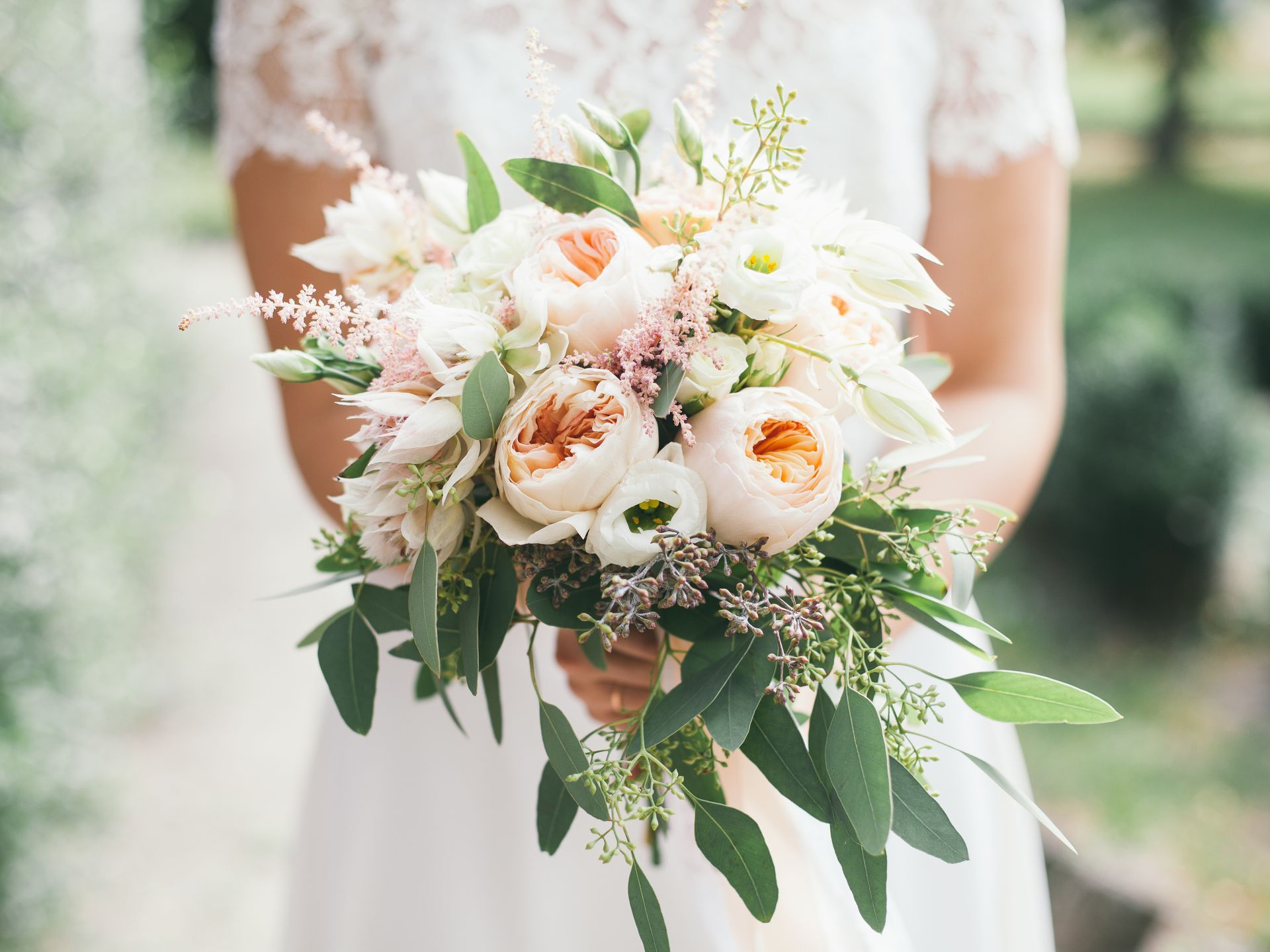 a bride in a white dress is holding a bouquet of flowers .