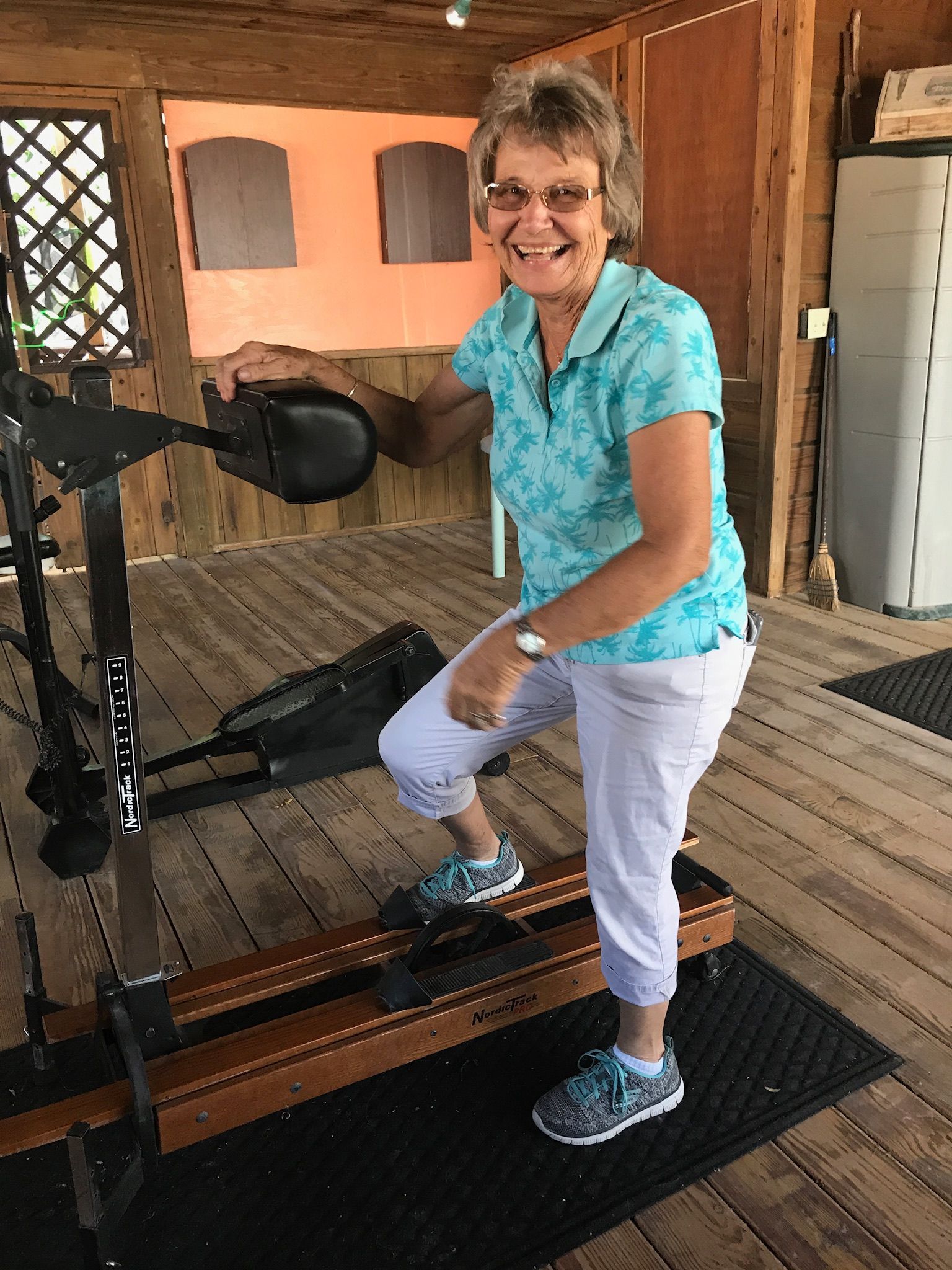 A woman is standing on a treadmill and smiling.