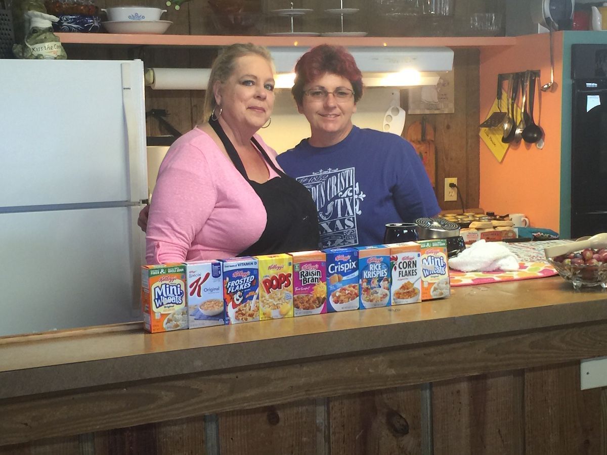 Two women standing behind a counter with boxes of cereal on it