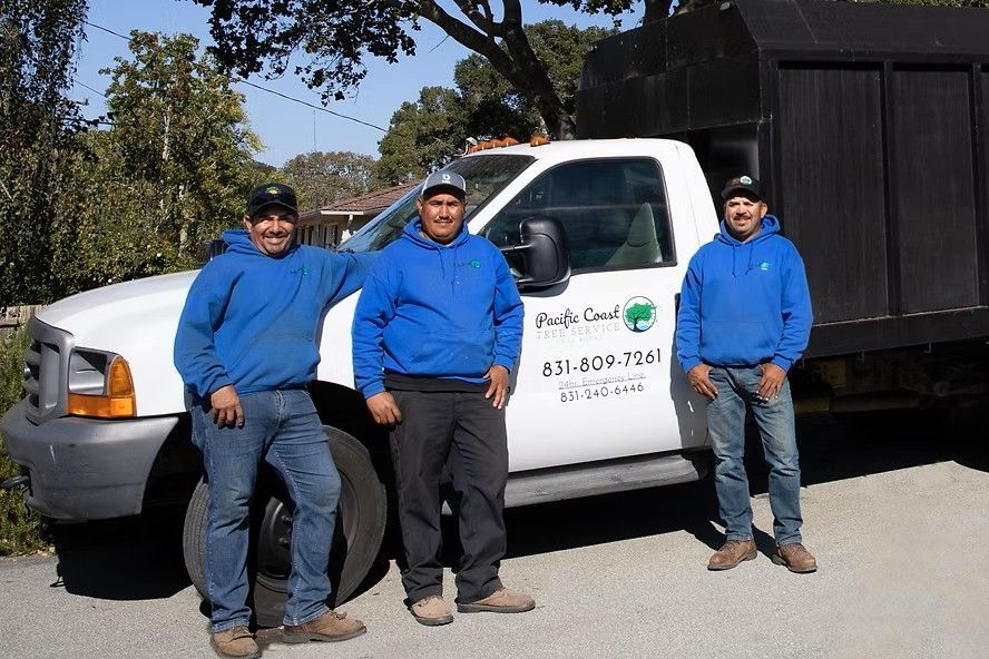 Three men are standing in front of a white truck.