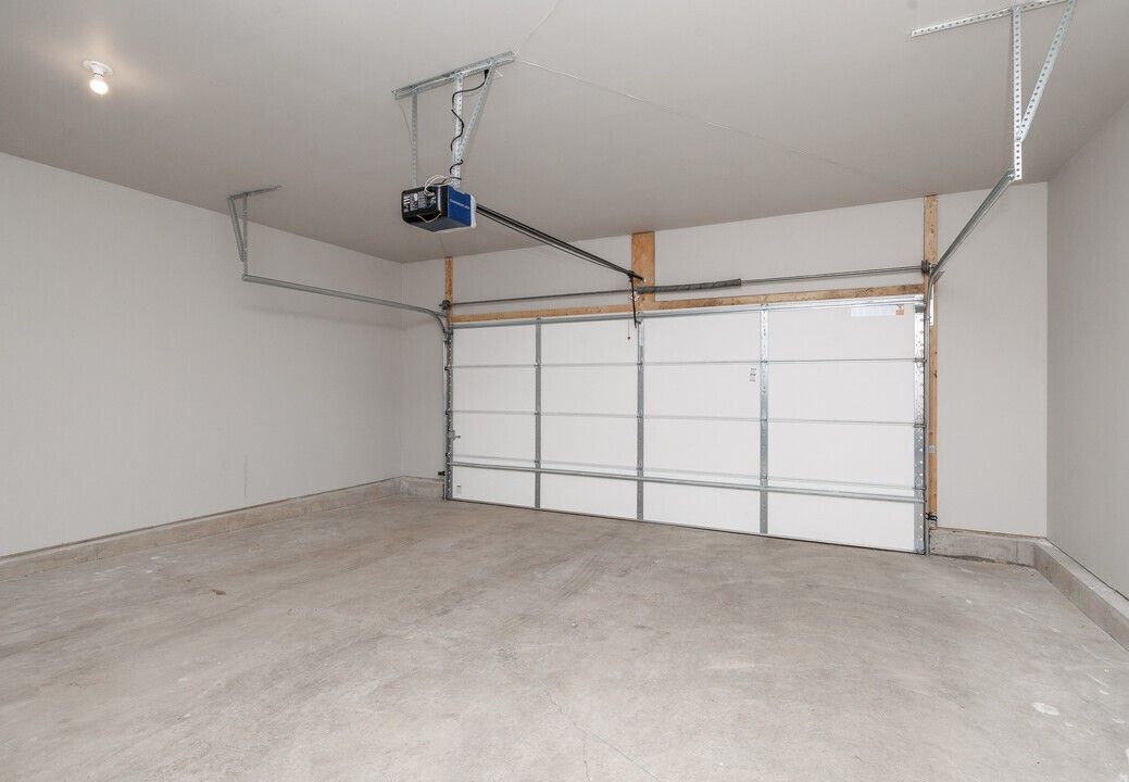 An empty garage with a garage door open and a garage door opener.