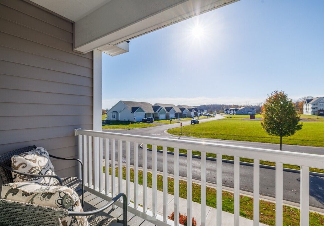 A balcony with a chair and table overlooking a residential neighborhood.