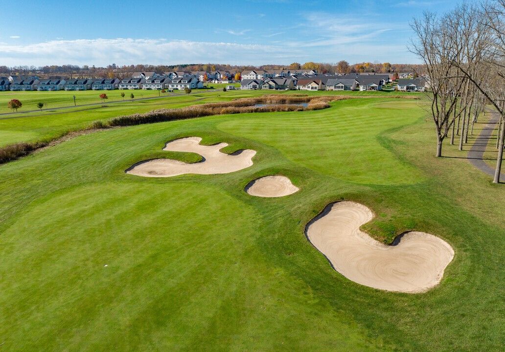 An aerial view of a golf course with bunkers and trees.