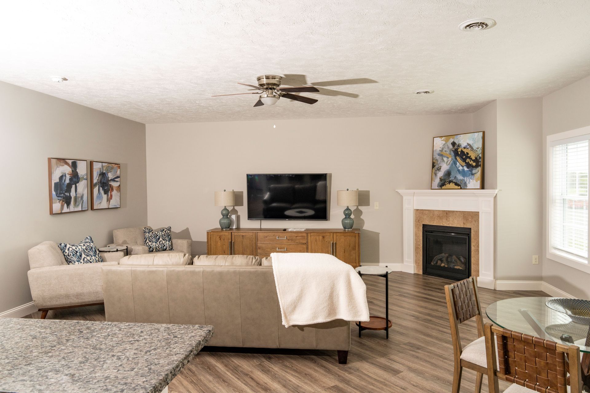 A living room with a couch , fireplace , television and ceiling fan.