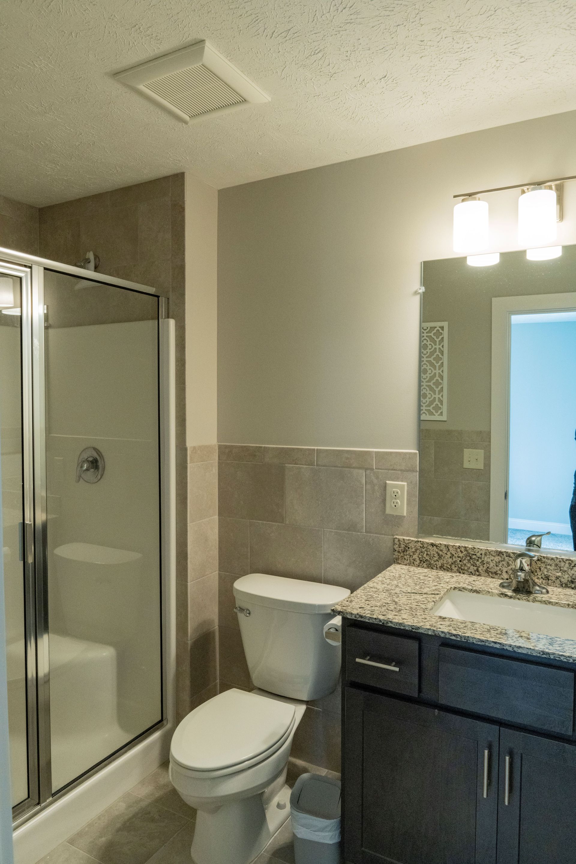 A bathroom with a toilet , sink , shower and mirror