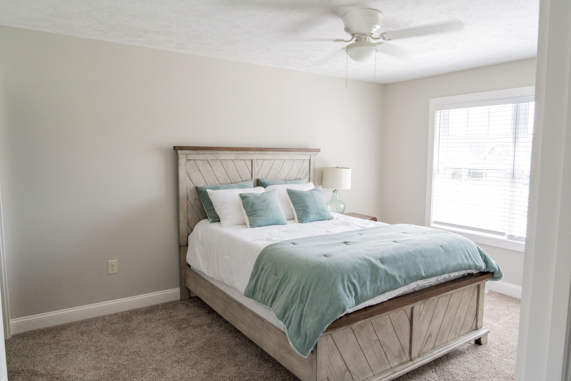 A bedroom with a bed and a ceiling fan.