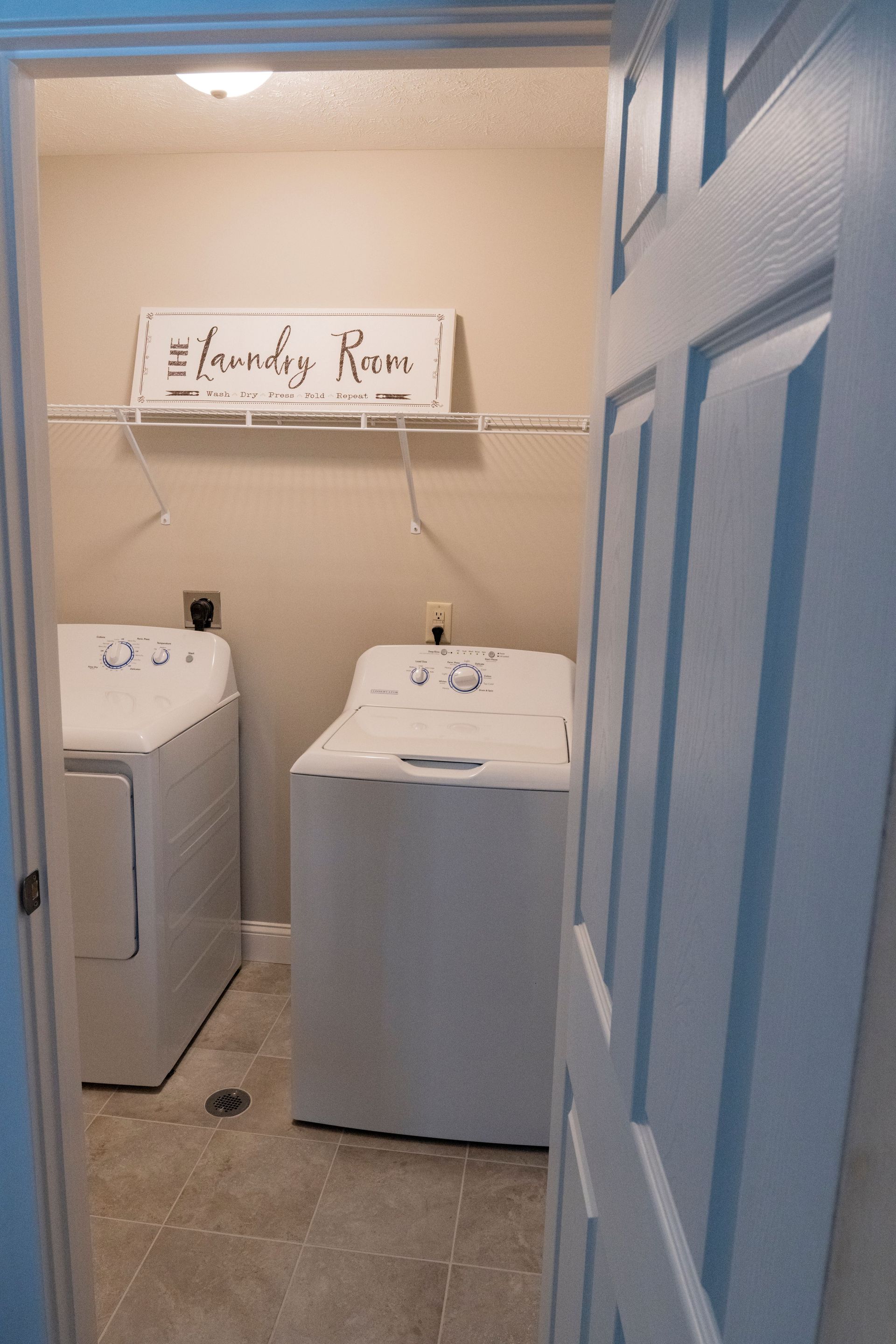 A laundry room with a washer and dryer and a sign on the wall.