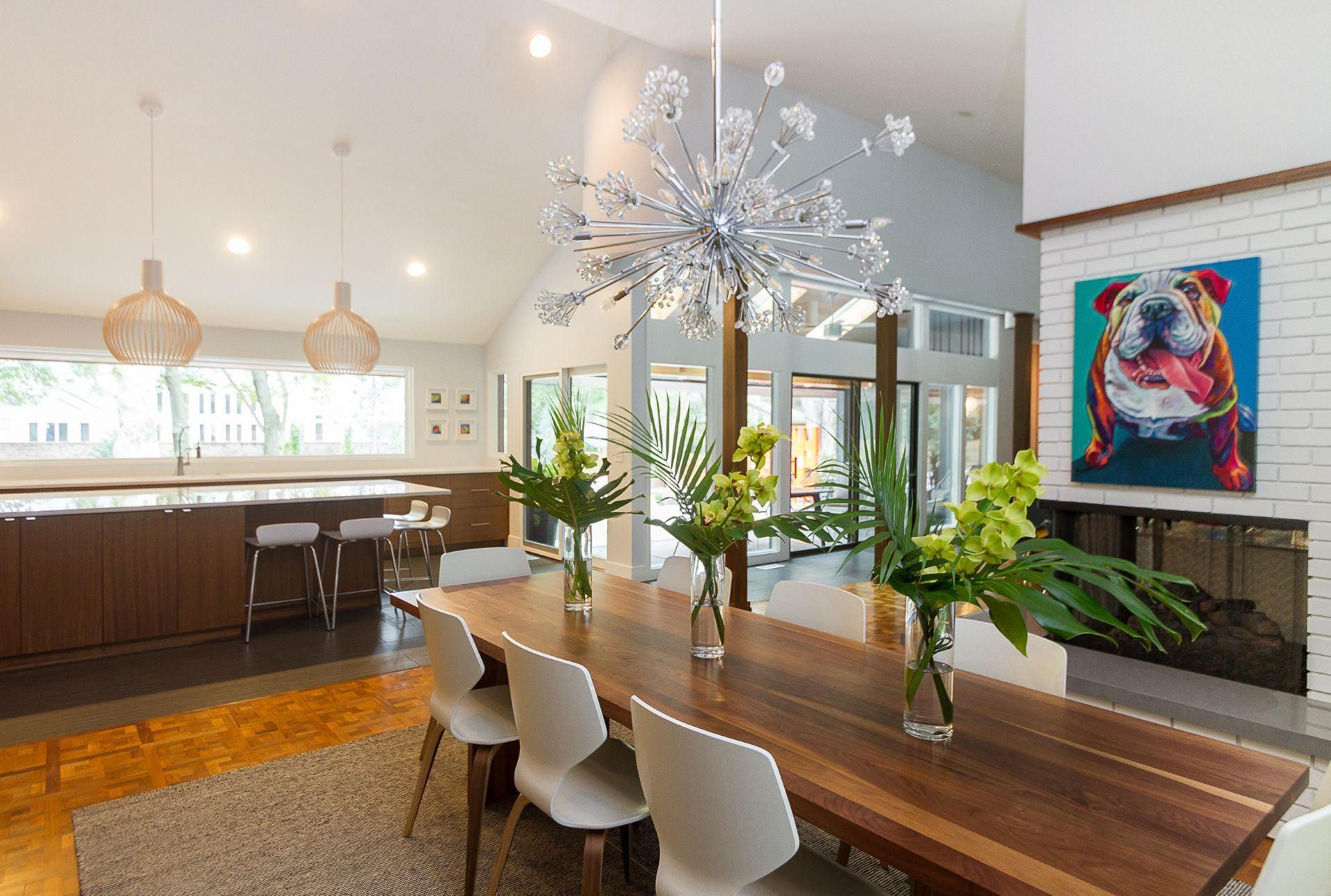 A dining room with a long wooden table and white chairs.