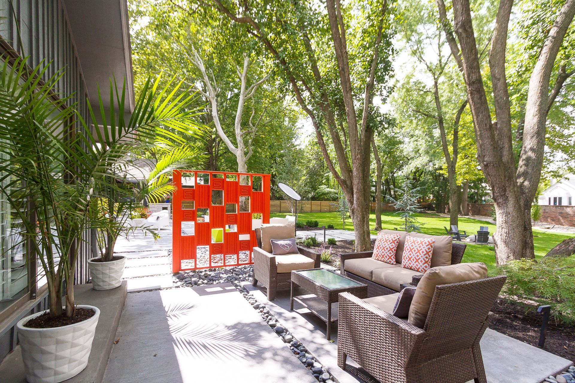 A patio with a couch , chairs , tables and a red screen.