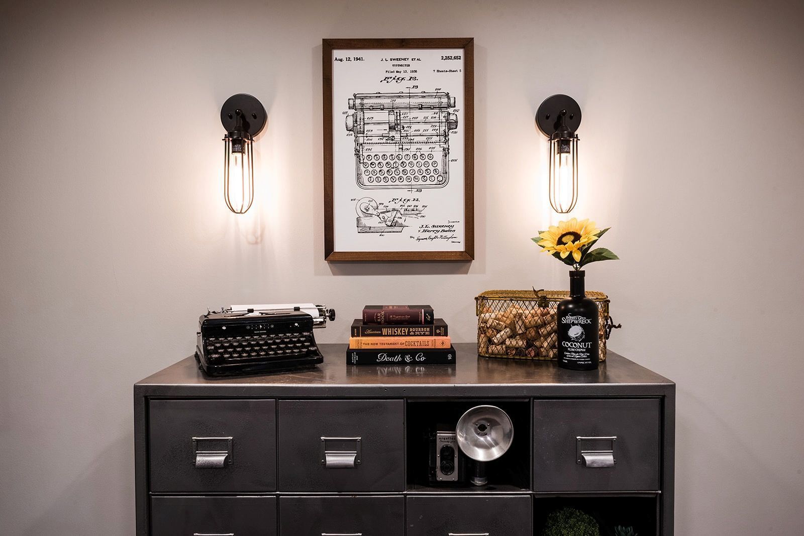 There is a picture of a typewriter on the wall above a dresser.