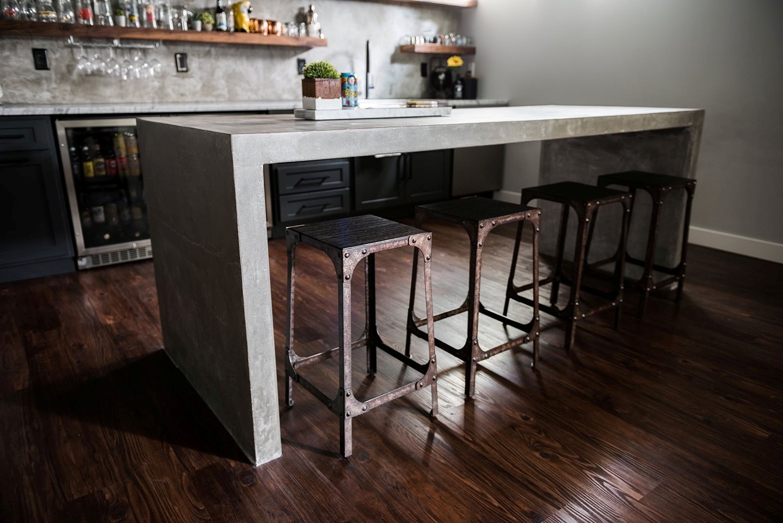 A kitchen with a concrete island and stools.
