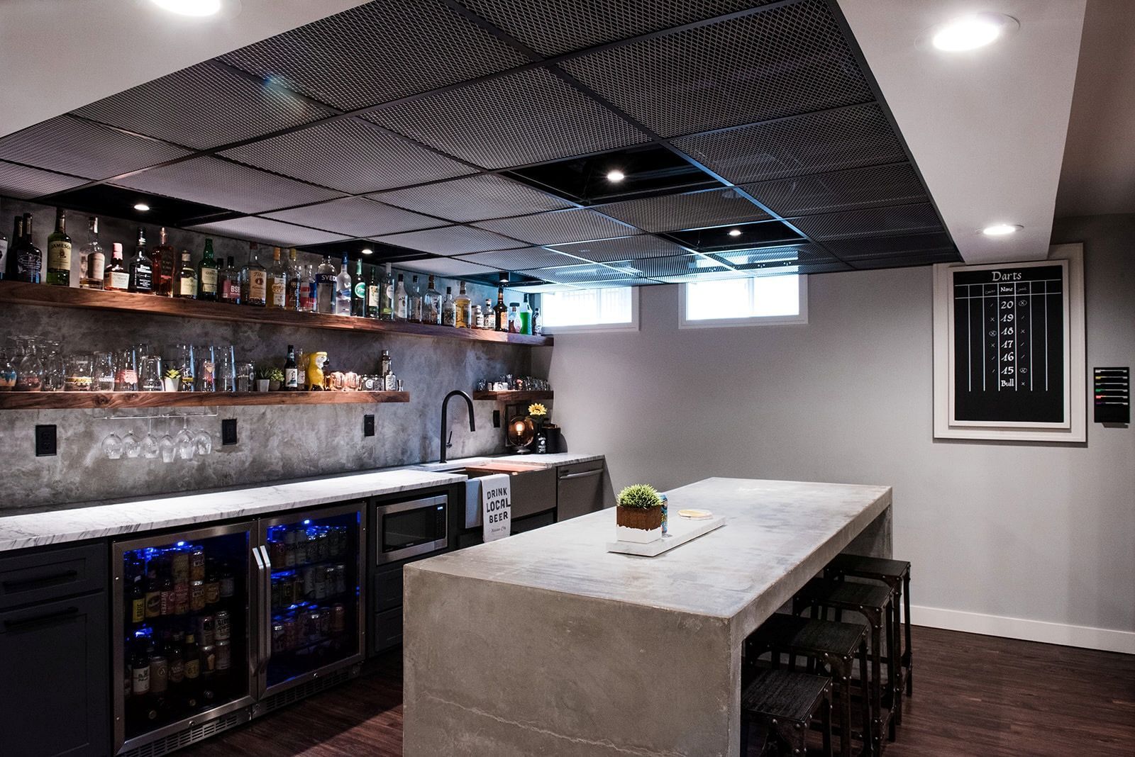 A kitchen with a large island and a lot of bottles on the shelves.