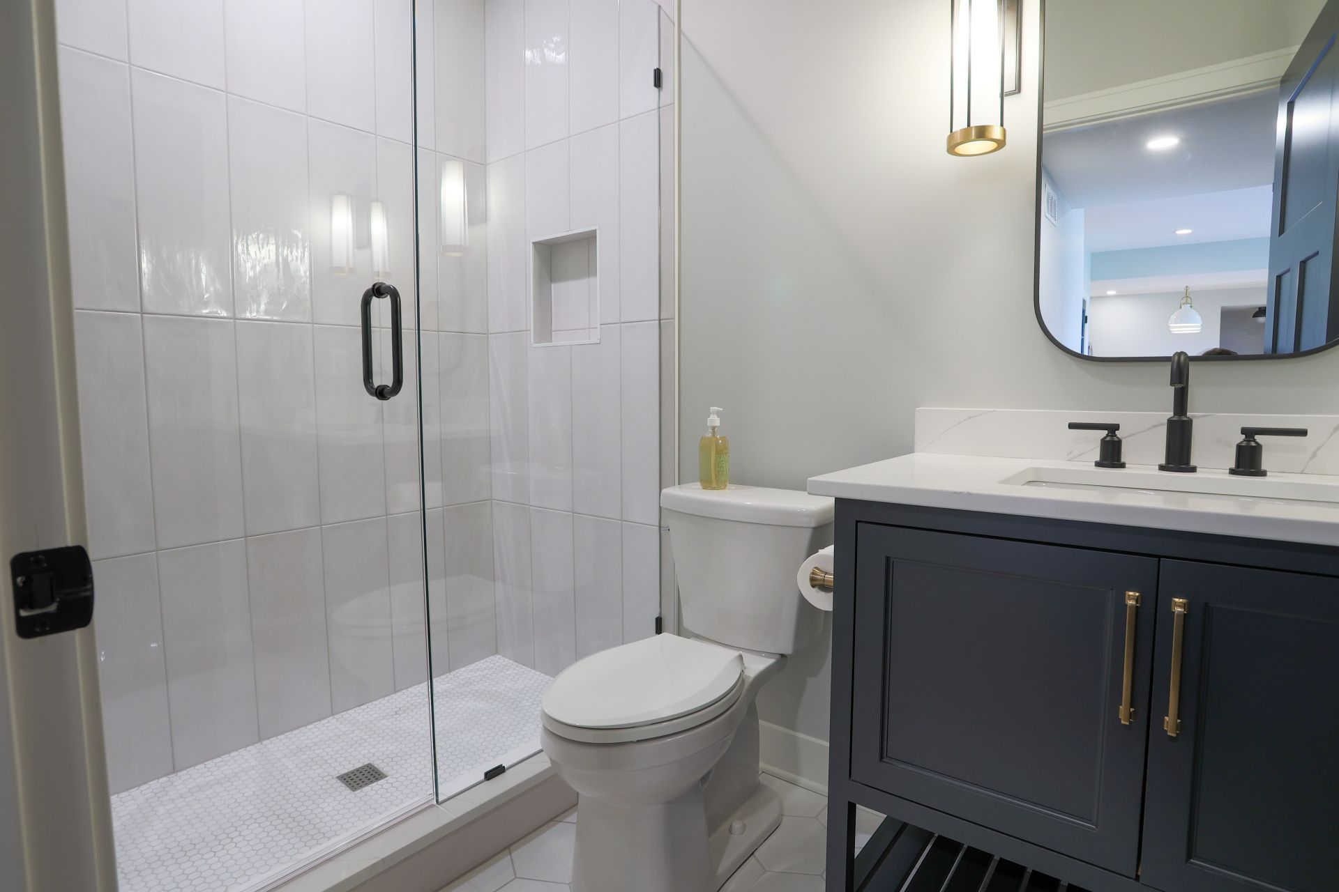 A bathroom with a toilet , sink , shower and mirror.
