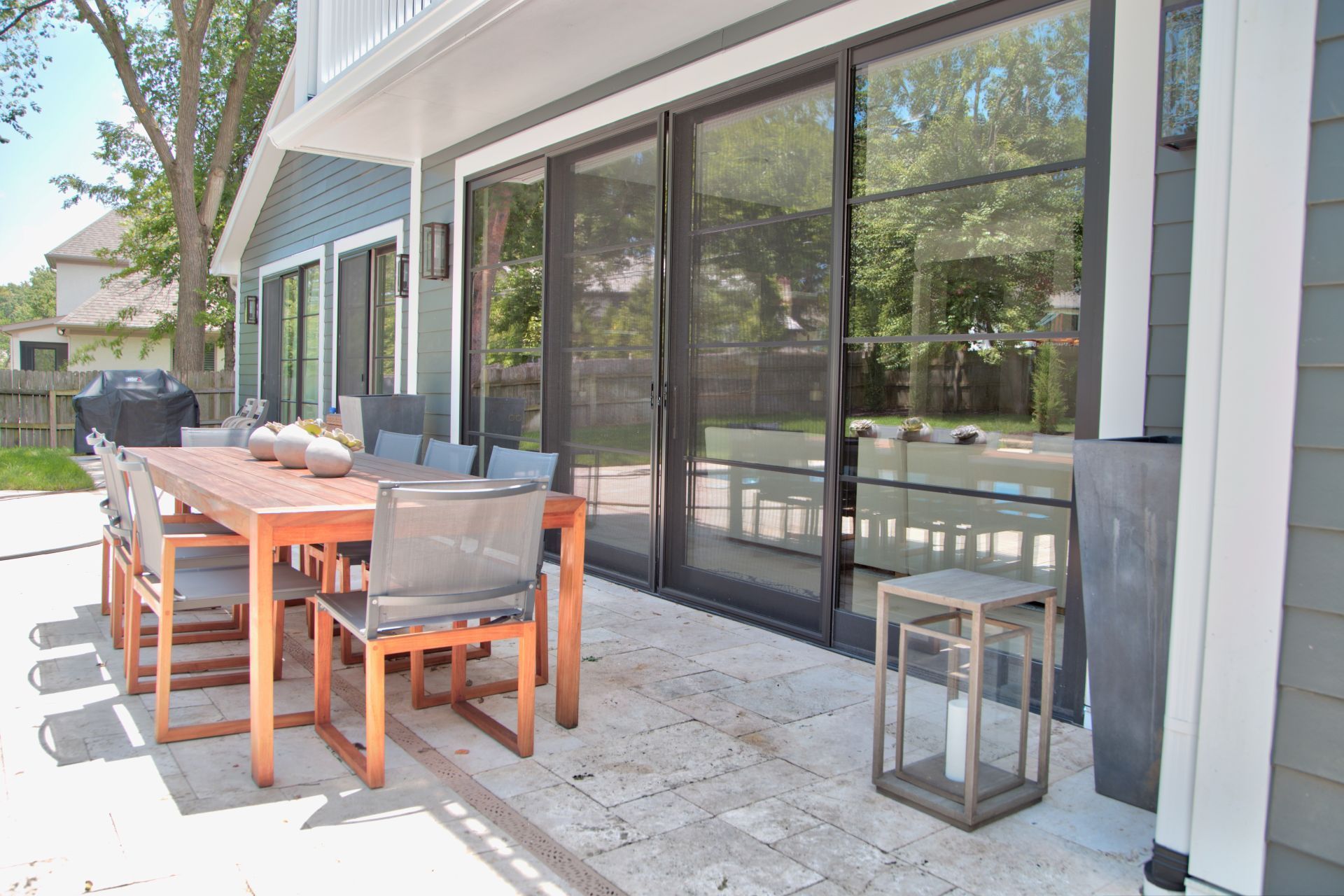 There is a large table and chairs on the patio of a house.